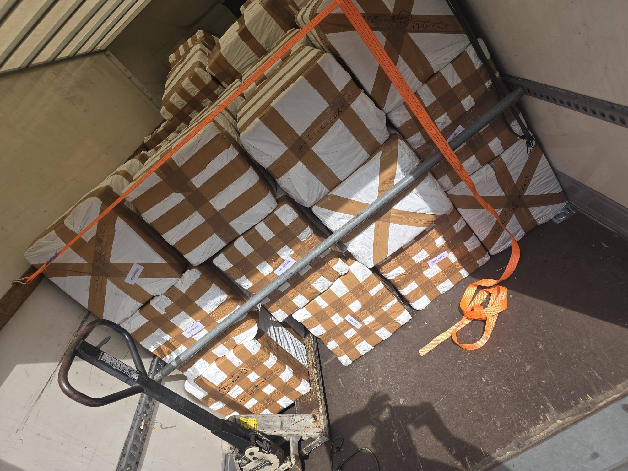 Taped boxes stacked high and held with orange ratchet straps