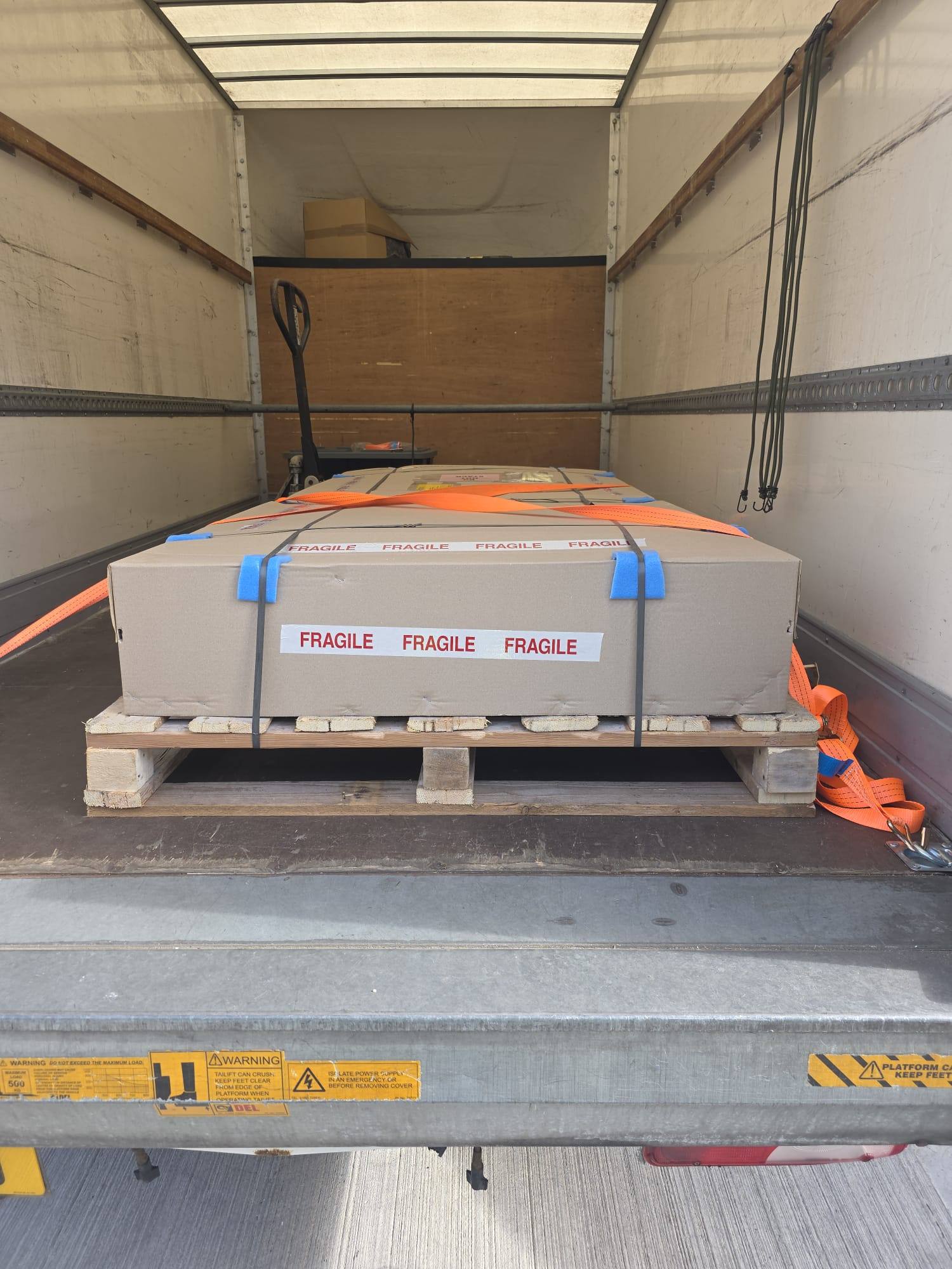 A fragile crate on a pallet, strapped at the back of the van