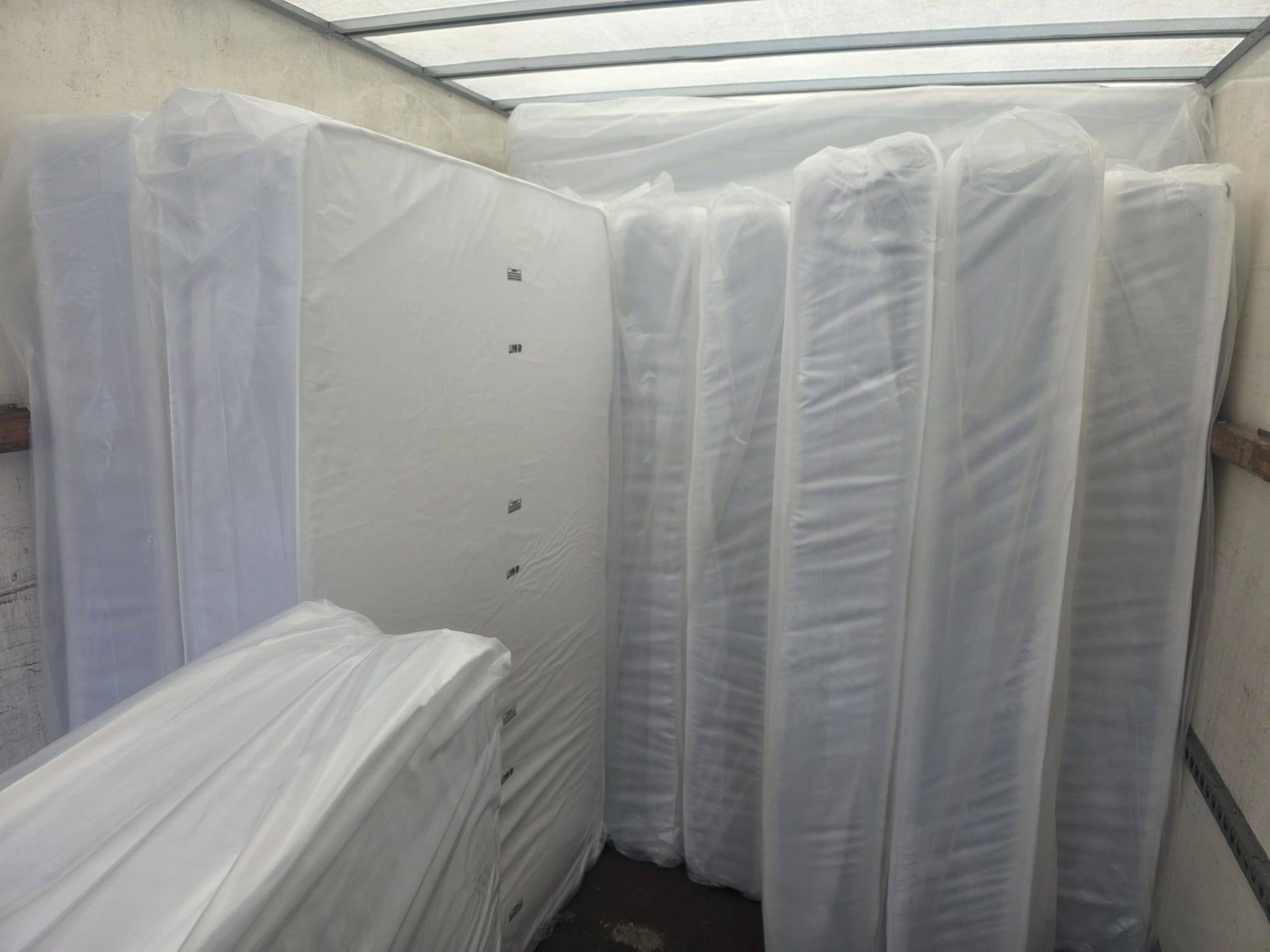 Mattresses wrapped in plastic and stood upright in the van